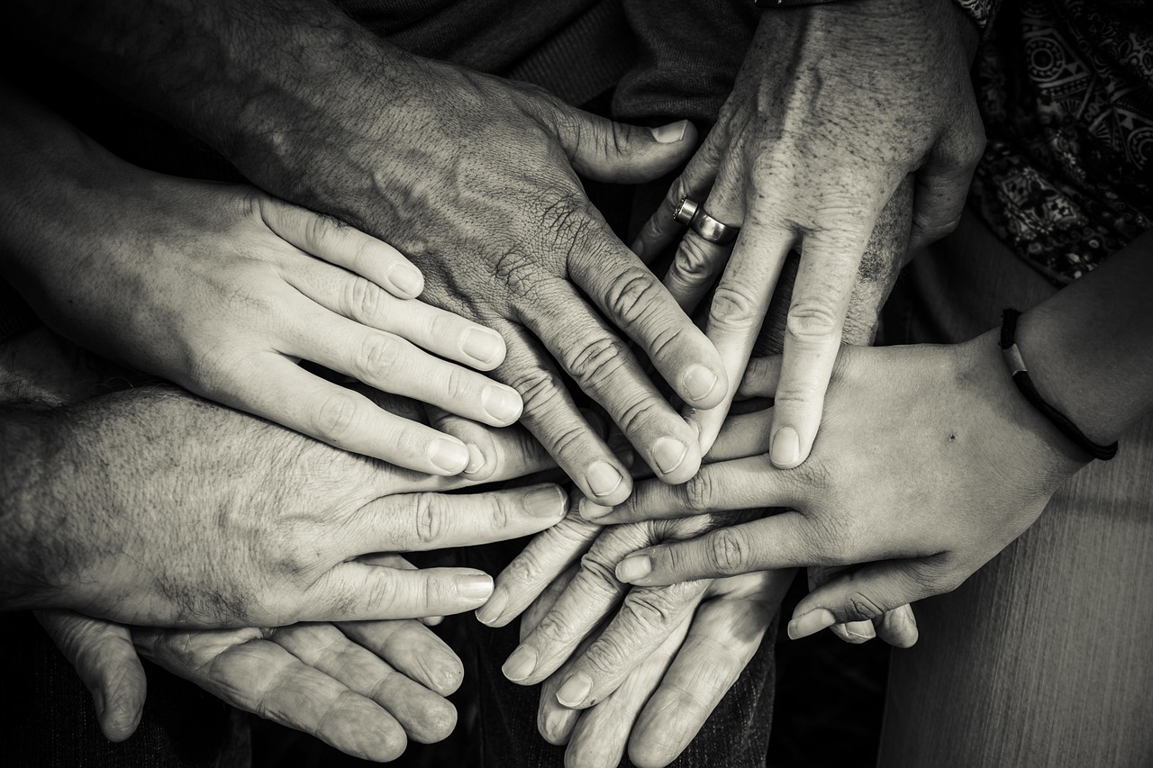 A number of hands from different people are resting on top of one another.